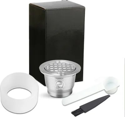 A set of reusable coffee capsules and accessories, including a brush and scoop, are displayed against a white background.