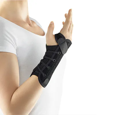 A person wearing a white t-shirt and a black wrist brace on their left arm.