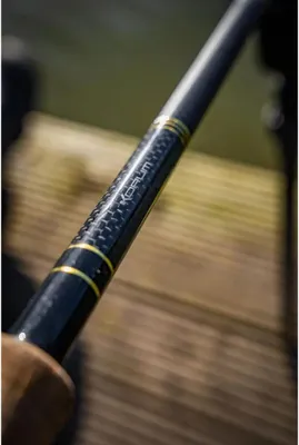A close-up shot of a fishing rod with gold accents and carbon fiber detailing.