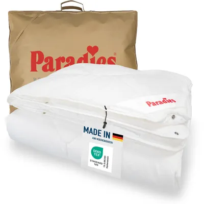 A folded white duvet is presented in front of a brown fabric bag with the brand logo. A tag with product information is attached to the duvet.