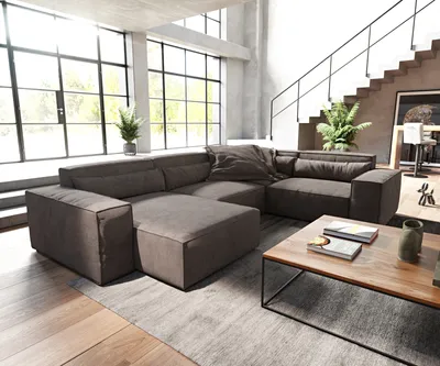 A modern living room with a large sectional sofa, coffee table, and staircase.