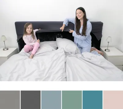 A mother and daughter are on a bed, pulling back a headboard cover.