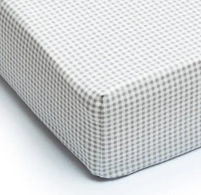 A close-up view of a folded baby crib sheet with a gingham pattern.