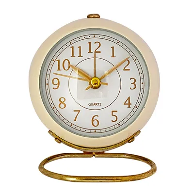 A close-up studio shot of a beige and gold alarm clock on a white background.