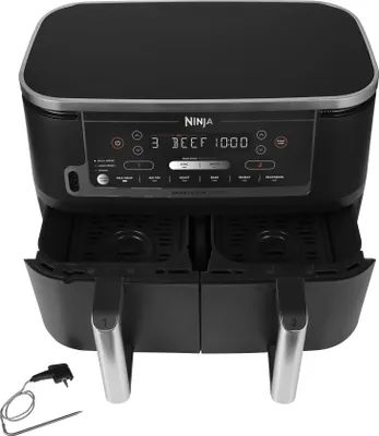 A black Ninja Foodi Max Dual Zone air fryer with its control panel and dual baskets visible, placed on a white background. A thermometer probe accessory is also shown.