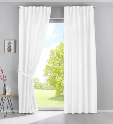 A room with a large window covered by white curtains, with a view of trees and a field outside.