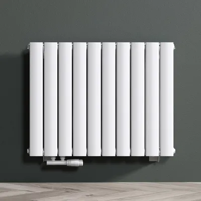 A white radiator is mounted on a dark gray wall above a light wooden floor.