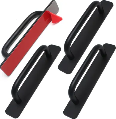 Four black door handles with adhesive backing are displayed against a white background. One handle in the top left corner shows the red adhesive backing being peeled off.