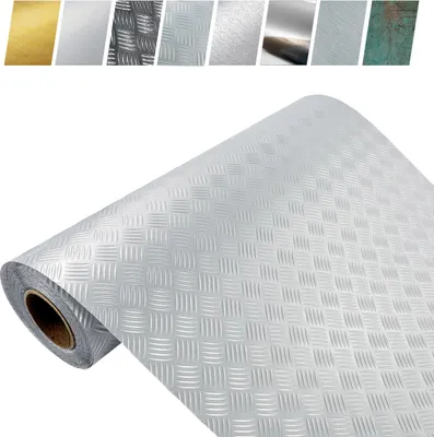 A roll of silver textured material is partially unrolled and lying diagonally across a white background. Above the roll, there are several small swatches of different metallic textures and colors.