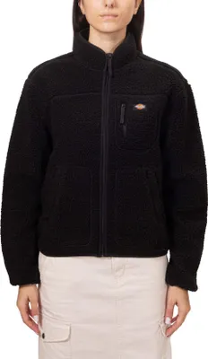 A woman is wearing a black fleece jacket and a light-colored skirt.