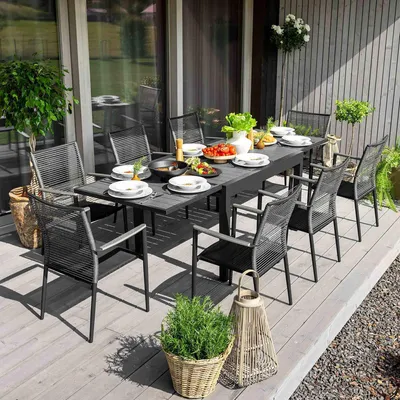 An outdoor dining set on a wooden deck, with food and drinks on the table.