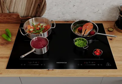 A modern induction cooktop with pots and pans containing food, set on a kitchen counter.