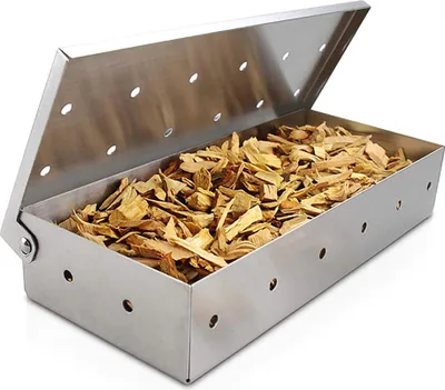 A stainless steel smoker box filled with wood chips, shown with its lid open.