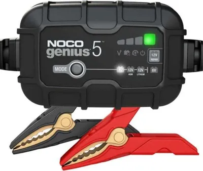 A black battery charger with red and black clamps attached.