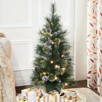 A decorated Christmas tree with presents underneath, in a room with curtains and a blanket.