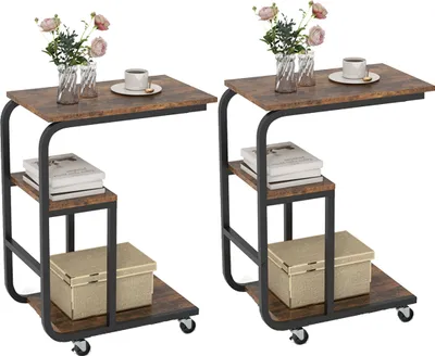 Two C-shaped side tables with a rustic wood finish and black metal frames are shown side-by-side against a white background. Each table has a top surface, a middle shelf, and a bottom shelf, with the bottom shelf holding a decorative box. The tables are on