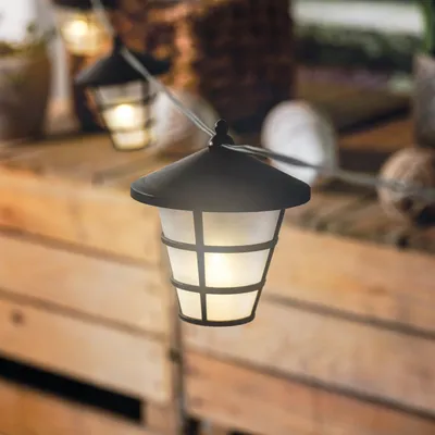 A string of solar-powered lantern lights hanging over a wooden surface.
