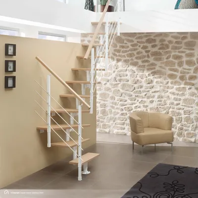 A modern staircase with wooden steps and white railings in a room with a stone wall and a chair.