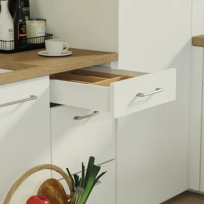 A close-up view of a white kitchen drawer system with a wooden countertop and a basket of produce.