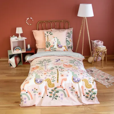 A child's bedroom with a bed made up with unicorn-themed bedding.