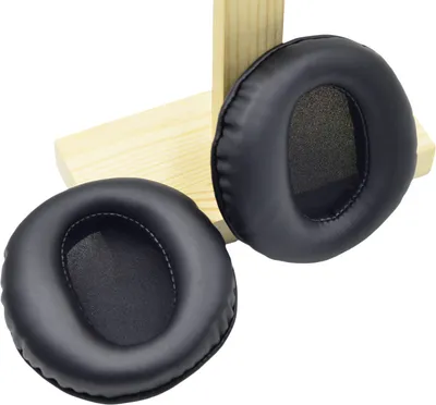 Two black headphone ear pads are shown on a wooden stand against a white background.