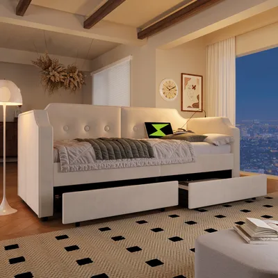 A cream-colored daybed with storage drawers in a well-lit room with a city view at night.