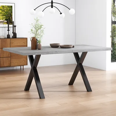 A dining table with a concrete-look top and black X-shaped legs, set in a modern dining room.