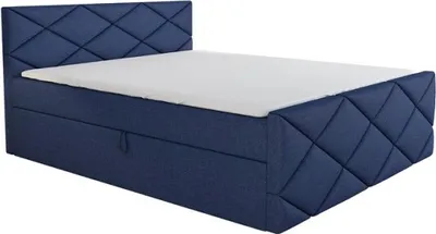 A blue upholstered boxspring bed with a white mattress and a diamond-stitched headboard and side panels, shown from a diagonal angle.