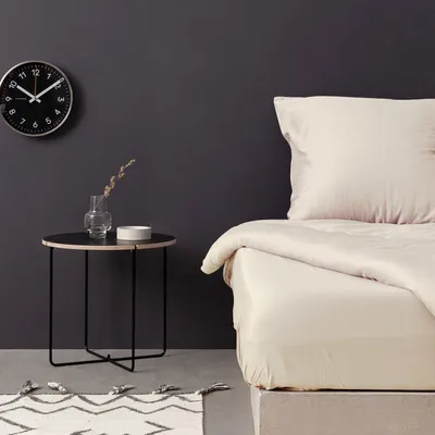 A bedroom scene with a bed, a side table, and a clock.