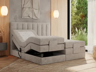 A bedroom scene with an adjustable bed, bedside table, and a window overlooking greenery.