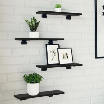 Four black wooden shelves are mounted on a white brick wall, each displaying decorative items.