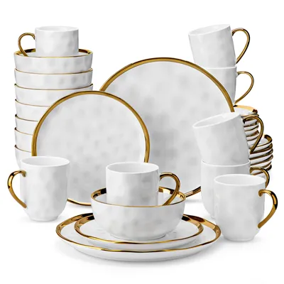 A collection of white ceramic dinnerware with gold trim, including plates, bowls, and mugs, arranged in a display.