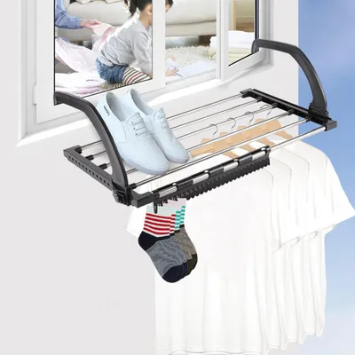 A drying rack attached to a window, with clothes and shoes on it.