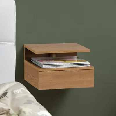 A wooden nightstand mounted on a green wall, next to a white headboard and a patterned duvet.
