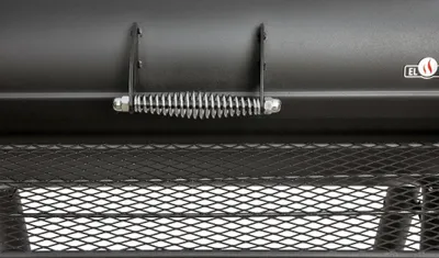 A close-up view of a black smoker grill's spring-loaded handle and wire mesh shelf.