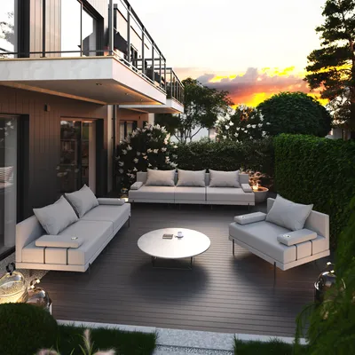 A modern outdoor patio with a grey sectional sofa set and a coffee table, set against a backdrop of lush greenery and a sunset sky.