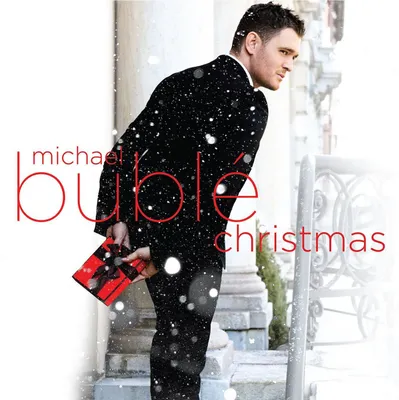 Michael Buble holding a Christmas gift while snow falls.