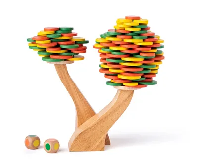 A wooden balancing game shaped like two trees with colorful discs stacked on them, and two dice in front.