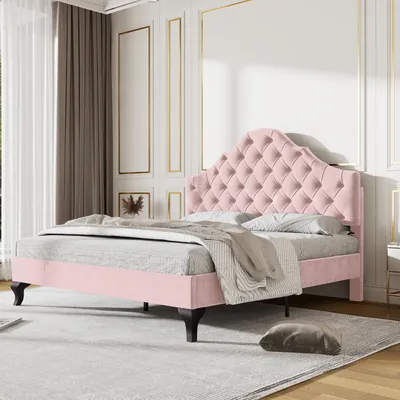 A pink upholstered bed with a tufted headboard is shown in a bedroom setting.