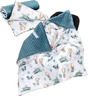 A baby blanket with a plane and hot air balloon pattern, laid out and partially rolled.