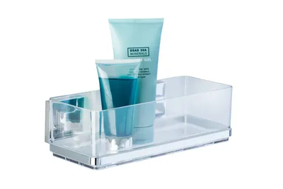 A clear acrylic shower caddy with two tubes of toiletries inside, mounted on a white background.