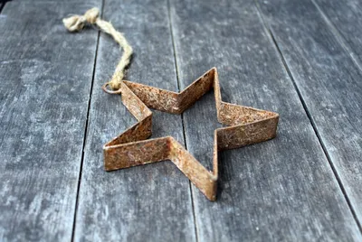 A rusty star-shaped cookie cutter is placed on a weathered wooden surface.