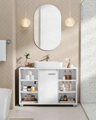 A white bathroom vanity with a sink and mirror above it, set against a beige herringbone tile wall.