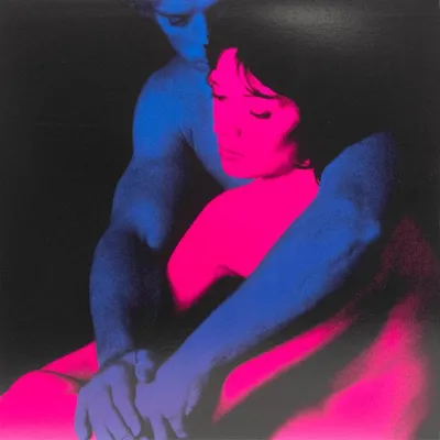 A couple embracing, bathed in blue and pink light.
