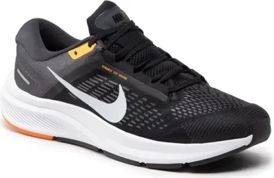 A black Nike running shoe with white and orange accents is shown from the side against a white background.