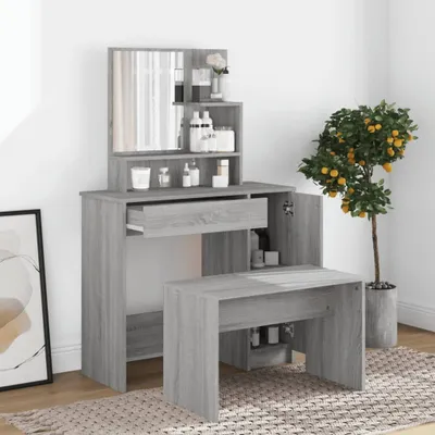 A vanity table with a mirror and stool, set up in a room with a plant and artwork.