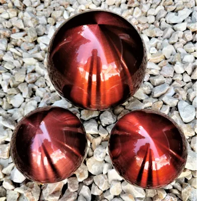 Three metallic red decorative spheres are placed on a bed of light gray and white gravel.