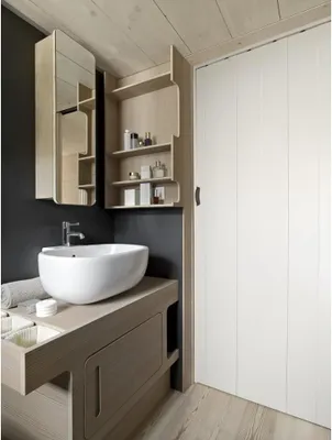A modern bathroom with a sink, vanity, and a closed door.