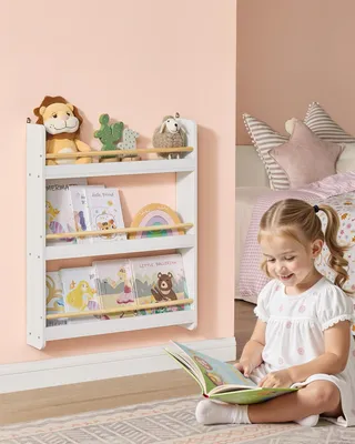 A child is reading a book in front of a small bookshelf.