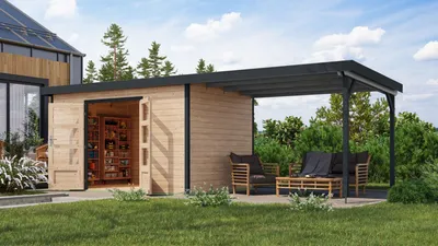 A wooden garden shed with an attached covered patio area, furnished with outdoor seating, set in a grassy backyard with trees and a blue sky with clouds.